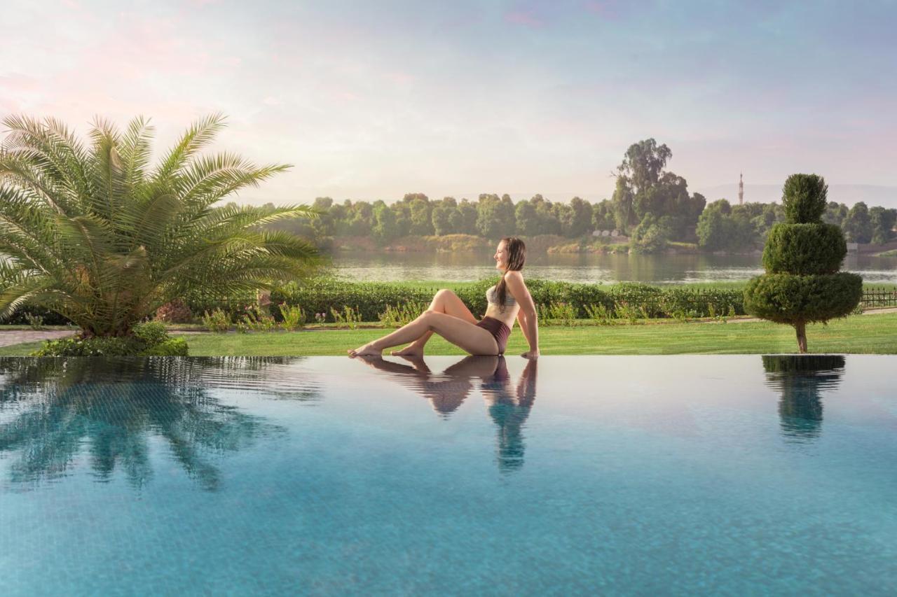 Jolie Ville Hotel & Spa Kings Island Luxor Buitenkant foto A woman sitting on the edge of a pool